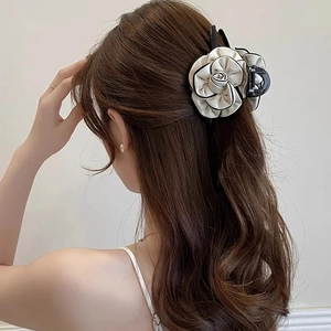 Detailed back view of a woman wearing a black and white camellia flower hair claw clip