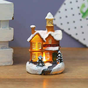 Detailed view of LED glowing Christmas resin snow house with warm orange light on wood