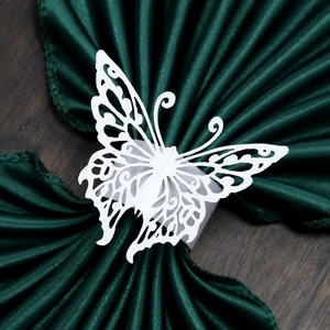 Detailed macro view of a laser-cut white butterfly paper napkin ring on green satin