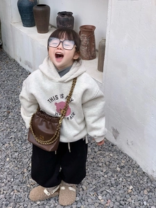 Detailansicht eines Kinder-Modeoutfits mit brauner Ledertasche und goldener Kette