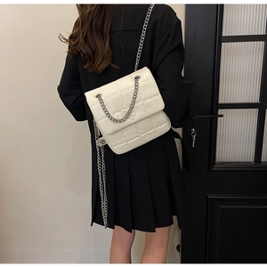 White quilted chain bag shown on model for high-contrast fashion styling detail