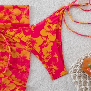Detail of hibiscus print bikini bottoms and matching sarong on a soft white beach rug