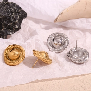 Close-up of vintage gold and silver twisted texture button earrings on white paper