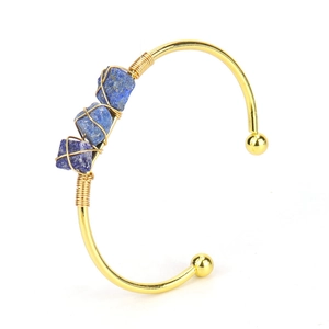 Close-up of three blue natural raw stones wire-wrapped on a golden open cuff bracelet