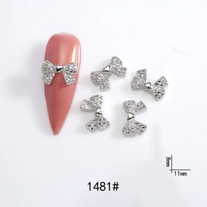 Detailed view of silver bow-shaped nail charms with sparkling rhinestones 11mm x 8mm
