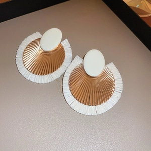 Detail of fan-shaped bohemian fringe earrings with gold metal and white pleated texture
