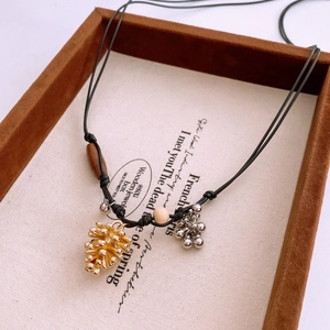 Détail d'un collier vintage avec pomme de pin dorée et pendentifs en forme de raisin