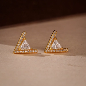 Macro shot of gold V-shaped stud earrings with micro-pave crystals and triangle zircon