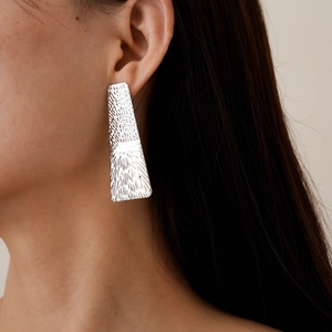 Detail of silver geometric trapezoid earring with textured hammered finish on model