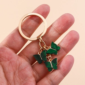 Detail of dark green marble acrylic butterfly charms on a gold ring keychain accessory