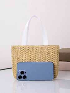 Detail of straw woven tote bag with white handles and textured fiber pattern