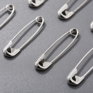 Macro shot of multiple silver plated steel safety pins scattered on a grey surface