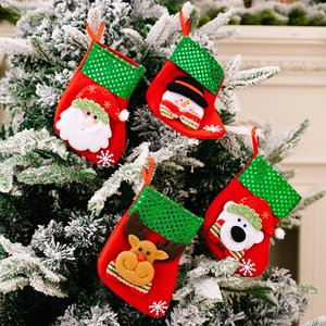 Detail of four festive Christmas stockings with sequins hanging on a snowy Xmas tree