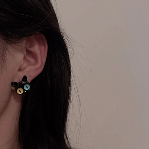 Close-up of black cat stud earring with heterochromia yellow and blue eyes on a model