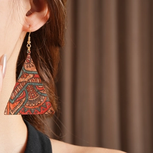 Close-up of vintage tribal geometric earrings featuring colorful leather print on model