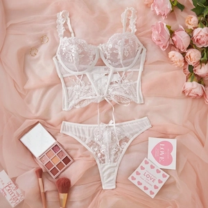 Detailed flat lay of white lace bustier set with floral embroidery and mesh ties