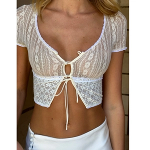 Dettaglio del crop top in pizzo bianco trasparente con lacci anteriori e chiusura a bottoni