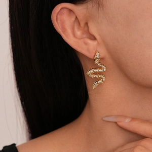 Close-up of a zircon-studded gold snake earring worn on a female model's ear