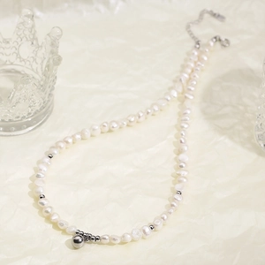 Vue détaillée d'un collier de perles d'eau douce avec perles argentées et pendentif rond