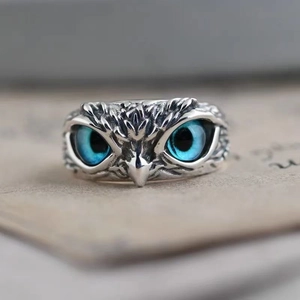 Vintage silver owl ring with deep blue eyes on a textured paper background