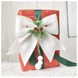 Close-up of white glitter bow with pine cones and berries for Christmas decor