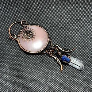 Detail of sun deity pendant with rose quartz, blue kyanite, and white crystal point
