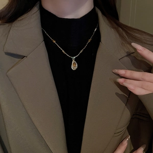 Détail d'un collier vintage en œil de tigre doré porté avec un blazer chic