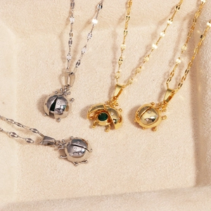 Detail of ladybug pendants with opening wings and green crystals on velvet display tray
