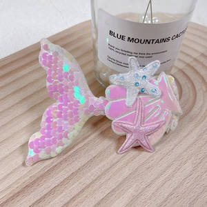 Detailed close-up of glittery pink mermaid tail hair clip with seashell and starfish