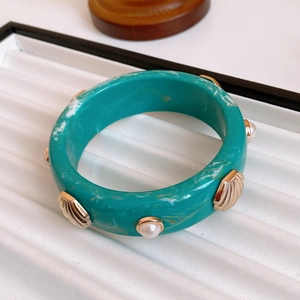 Macro shot of turquoise marble resin bangle with gold shell and pearl embellishments