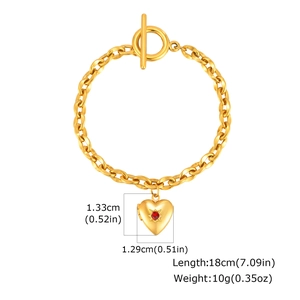 Dettaglio macro di un bracciale a catena con fibbia OT dorata, pendente a cuore e gemma