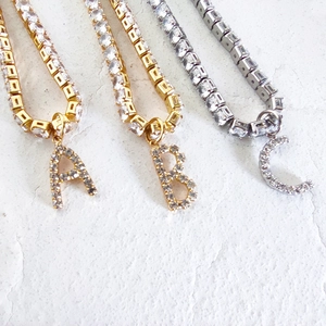 Detail of gold and silver tennis chains with crystal encrusted A B C letter pendants