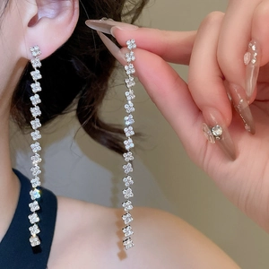 Close-up of sparkling silver tassel earrings with geometric chains and crystals