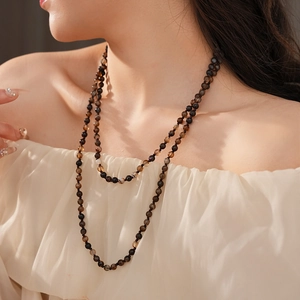 Detail of bohemian long beaded agate necklace with polished dark brown and black stones