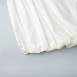 Détail de l'ourlet à volants sur une robe en coton blanc avec tissu plissé élégant