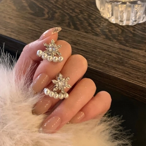 Elegant silver snowflake earrings featuring pearls and zircons on a model's hand