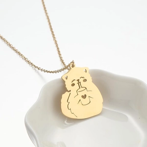 Close-up of golden stainless steel hollow cat pendant necklace on a white ceramic dish