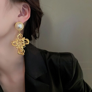 Detailaufnahme barocker goldener Kreuz-Ohrringe mit Perlensteckern im Retro-Stil Design.