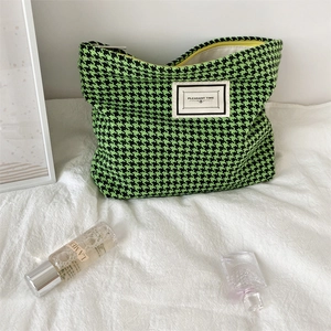 Detail of green houndstooth cosmetic bag with Pleasant Time label on soft fabric