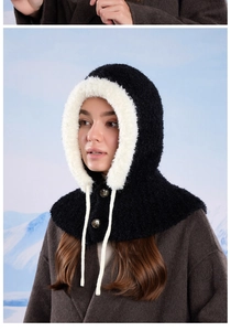 Detail of winter balaclava featuring black knit texture and white faux fur trim with buttons
