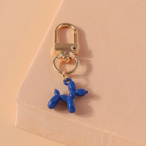 Close-up of blue balloon dog keychain with golden ring on a warm textured block