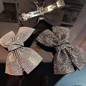 Three elegant bow hair clips with rhinestones and black fabric on reflective surface