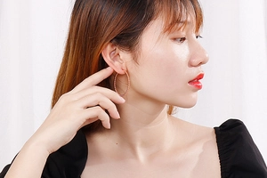 Detail of rose gold wide hoop earrings with delicate beaded texture on a female model