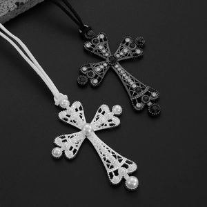 Détail de colliers croix gothiques avec perles et strass sur un fond de roche noire