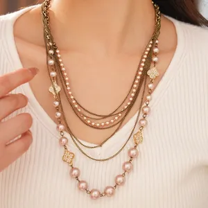 Multi-layer pearl necklace featuring crystal-encrusted clover pendants on copper chains