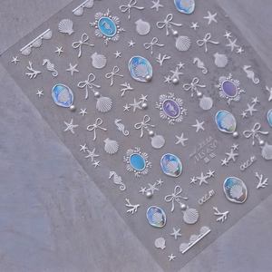 Macro detail of ocean-themed nail stickers with silver seahorse and pearl relief