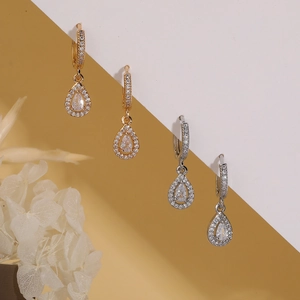 Elegant gold and silver teardrop earrings with crystals displayed with white flowers