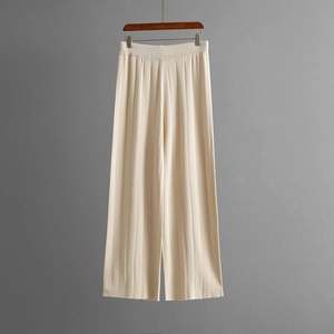 Detailed view of cream white knitted wide-leg trousers with elegant draped texture