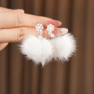 Detail showing white snowflake stud with a small pearl and fluffy fur ball earring