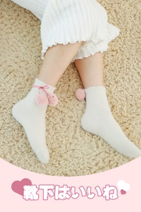 Close-up of white fleece home socks featuring pink ribbon bows and soft pom-poms
